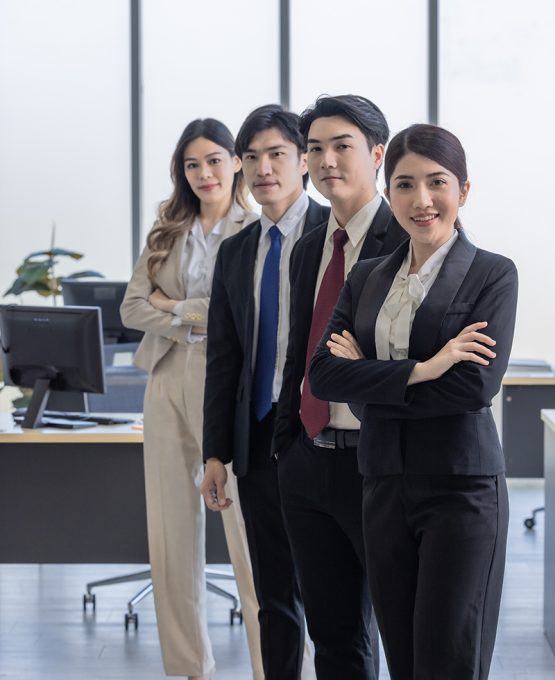 A team of four confident business professionals standing in a line with crossed arms in a modern office setting.symbolizing teamwork and success.